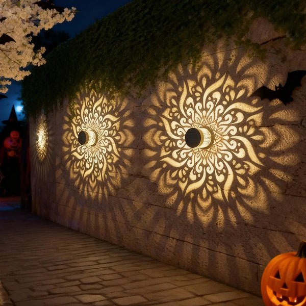 Lanterne solaire murale ajourée projetant un motif mandala lumineux sur un mur de façade