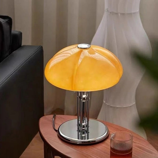 Lampe champignon en verre orange allumée sur une table d'appoint